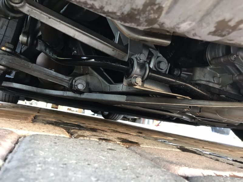 Vehicle undercarriage and suspension components viewed from below on a paved surface