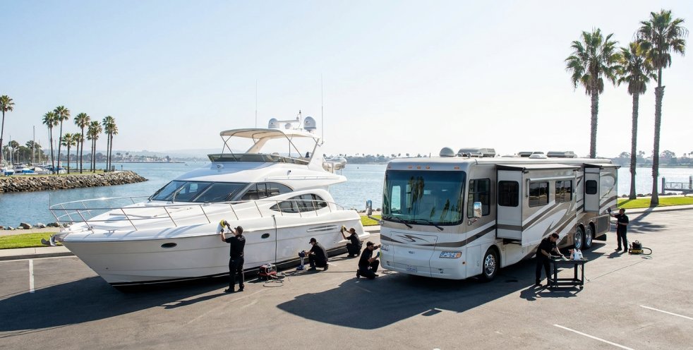 Boat and RV detailing crew cleaning a yacht and motorhome by the waterfront